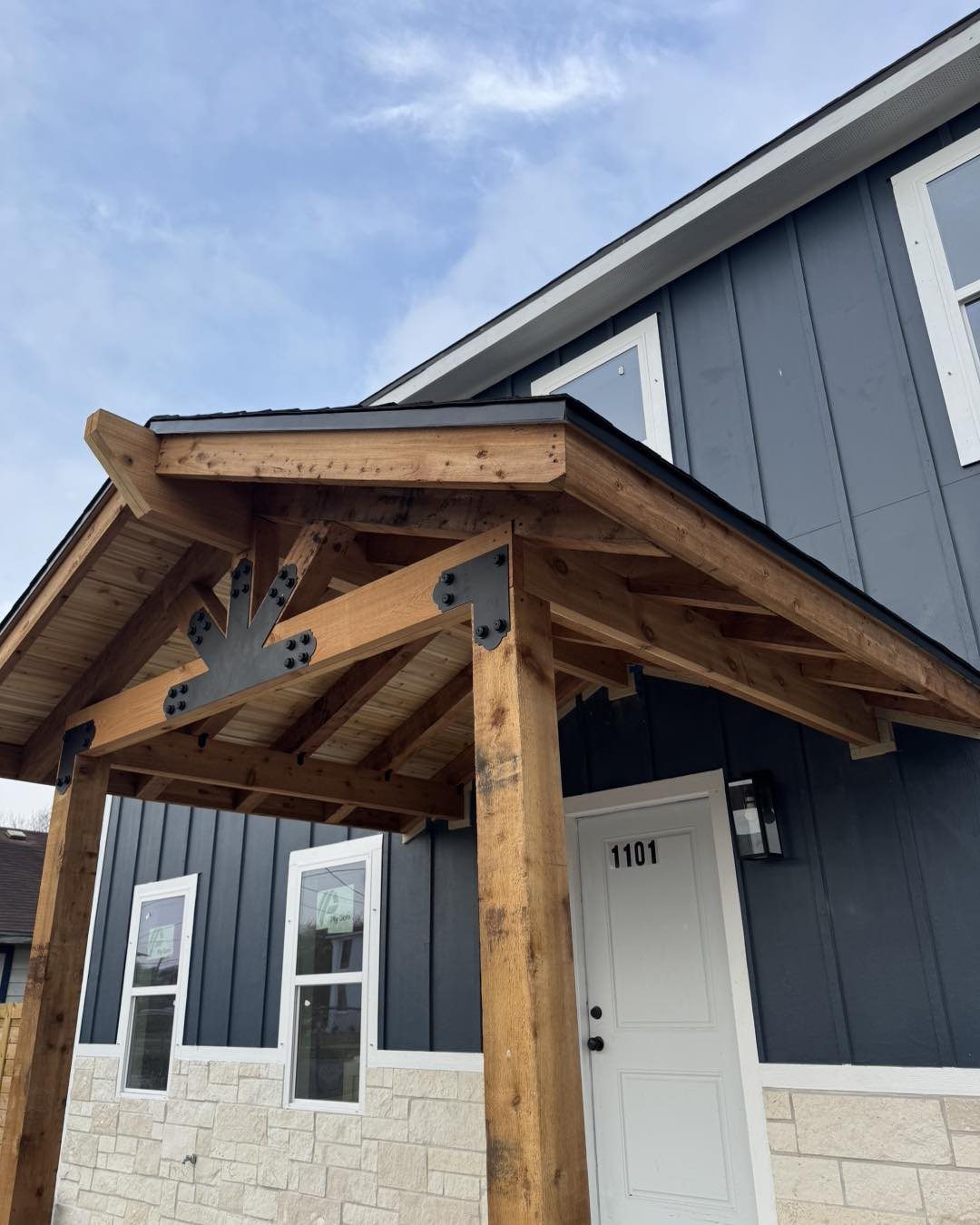 Exterior timber frame entry porch with board and batten siding and stone base